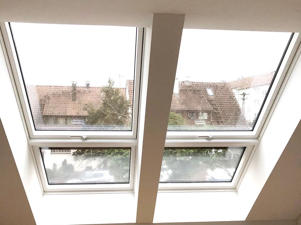 Deux fenêtres de toit vues de l’intérieur d’une pièce sous combles lumineuse