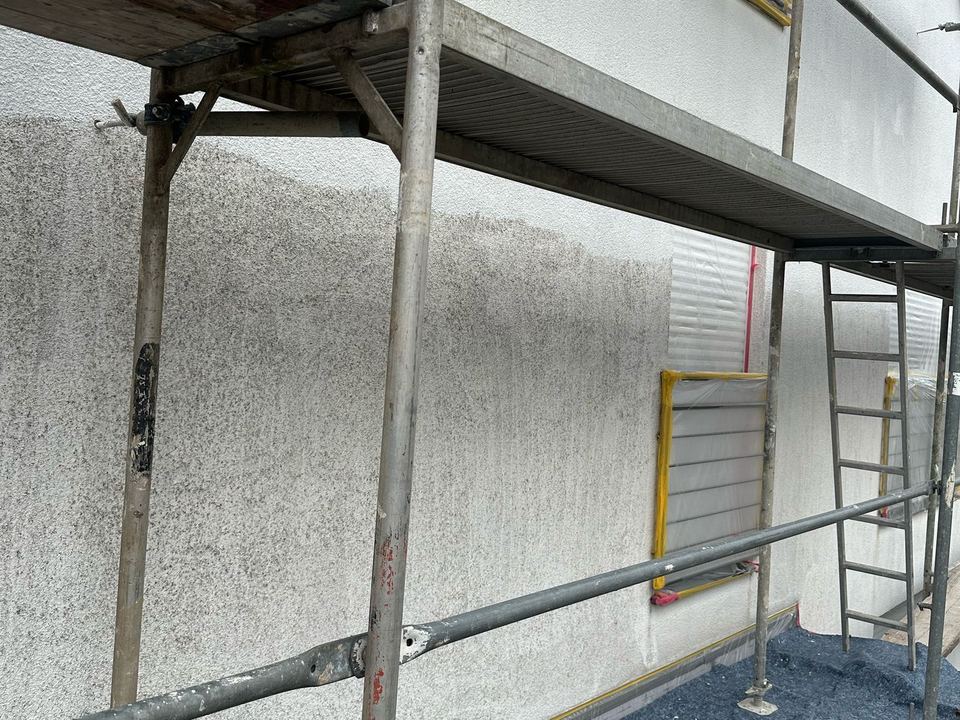 Façade enduite en travaux sur échafaudage, fenêtres protégées par un film