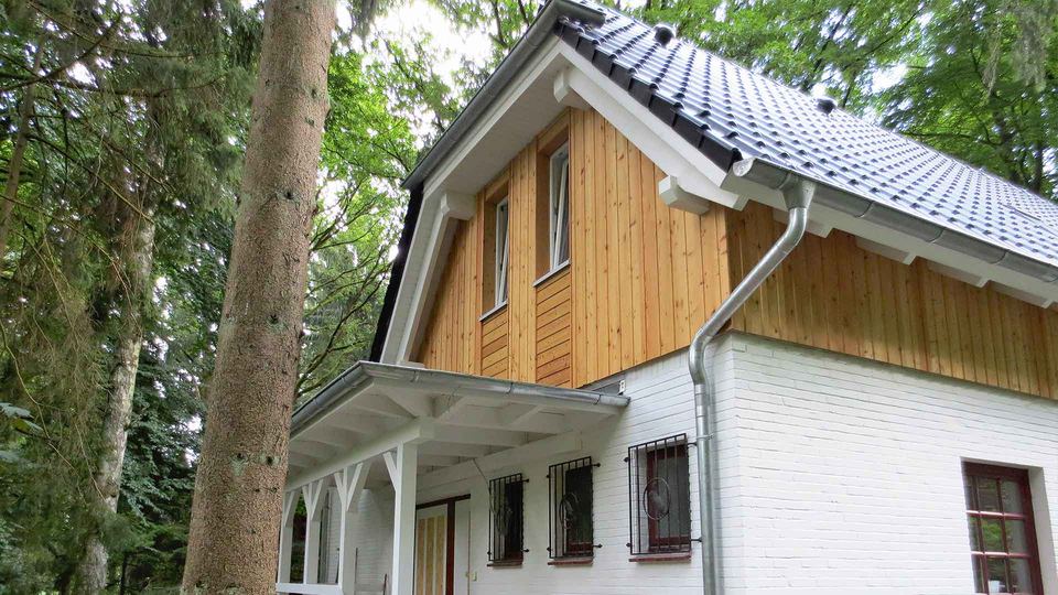 Pignon de maison habillé d’un bardage bois vertical au-dessus d’un rez-de-chaussée en brique peinte